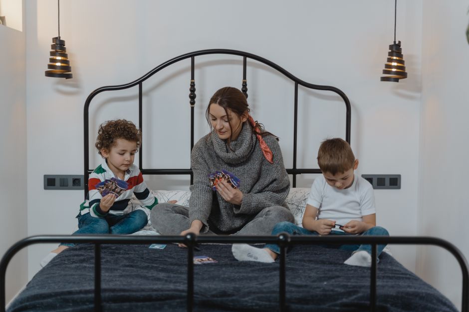 Mãe e filhos a jogar cartas num quarto acolhedor