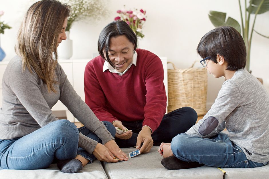Família a jogar cartas na sala de estar